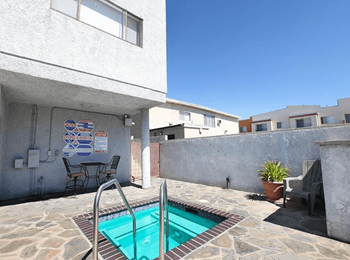 A pool in a backyard with a table and chairs.